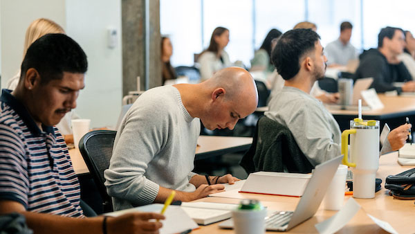 A classroom setting inside of a Watermark Institute session featuring a student writing notes.